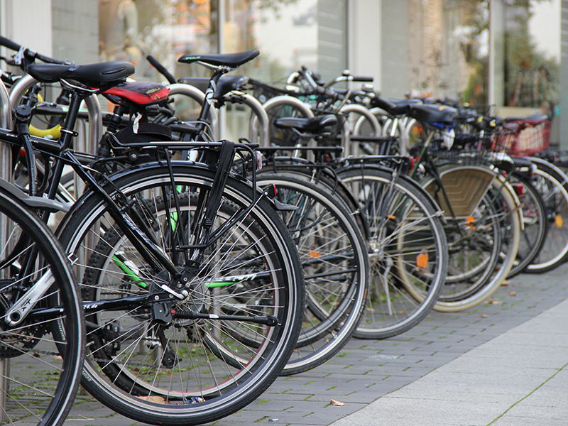Eine ganze Reihe parkender Fahrräder, im Bildausschnitt sieht man vor allen Dingen die Hinterreifen der Räder.