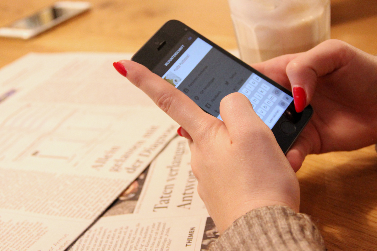 Eine Frau mit rot lackierten Fingernägeln tippt auf ihrem Smartphone eine Nachricht