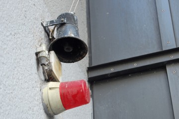 Rote Alarmleuchte und Lautsprecher an einer Hauswand.
