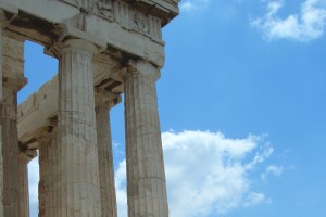 Nahaufnahme eines historischen Gebäudes im griechischen Baustil vor blauem Himmel.