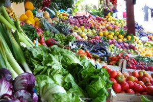 Blick auf einen bunten Marktstand mit verschiedensten Obst- und Gemüsesorten im Angebot.