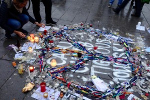 Auf einem Gehweg in Paris liegen Zeitungsausschnitte, Blumen und Kerzen in Gedenken andie Opfer des Anschölags auf die Redaktion der Satirezeitschrift Charlie Hebdo.