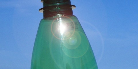 Nahaufnahme einer grünen Plastikflasche mit blauem Himmel im Hintergrund.