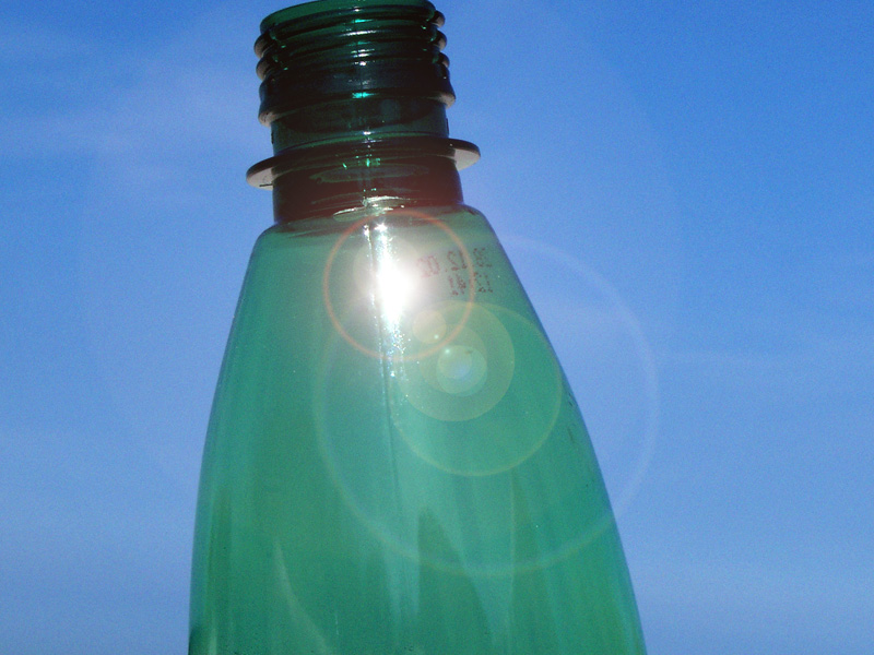 Nahaufnahme einer grünen Plastikflasche mit blauem Himmel im Hintergrund.