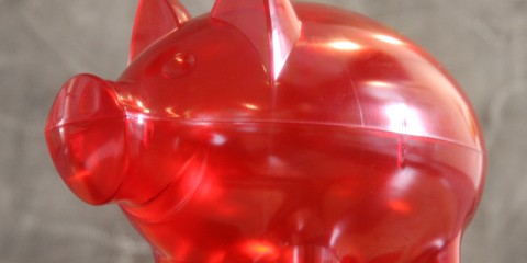 Nahaufnahme eines transparenten roten Sparschweines aus Plastik.