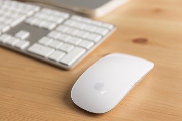 Detailaufnahme einer modernen Computertastatur und der dazugehörigen Mouse in weiß von Apple.