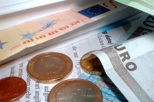 Nahaufnahme einiger Euro-Gelscheine und-Münzen nebst Unterlagen.