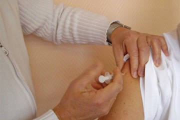 Impfung: der Bildausschnitt zeigt einen Mediziner, der einem Patienten eine Spritze in den Oberarm verabreicht.