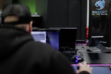 Ein in dunklen Sachen gekleideter Computerspieler sitzt vor seinem Rechner und spielt ein Computerspiel.