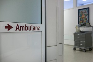 Blick durch eine offene Glastür im Krankenhaus, auf der Tür der Schriftzug "Ambulanz".